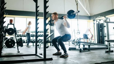 Jimnastik yeteneklerini sergileyen bir erkek sporcu, halter egzersizlerini kapalı bir tesiste antrenman rutinine dahil ediyor. Genç Atletler için Halter ile Performans Jimnastik Antrenmanını Yükseltmek