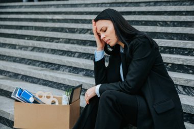 Merdivenlerde oturan bir kadının kasvetli görüntüsü, işini ve işsizliğini düşüncelere dalmış. İşsiz ve Yalnız Bir Kadın Hüzünlü bir ifadeyle Merdivenlerde Oturuyor