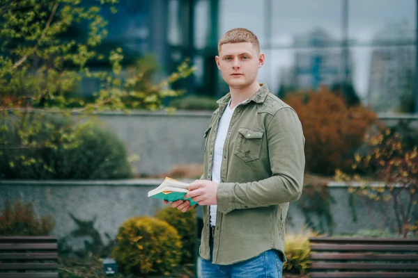 stock image This portrait of a male sitting with his book in an outdoor location captures his lovely and authentic expression. Urban Elegance Portrait of a Young Adult Male Sitting with Book Outdoors