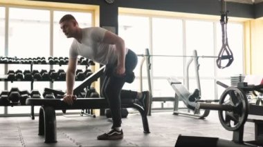 Fitness hedeflerine odaklanmış, kendini sporda halter kaldırmaya adamış bir adam. Odaklanmış genç bir adam halter kaldırma egzersizi yapıyor.