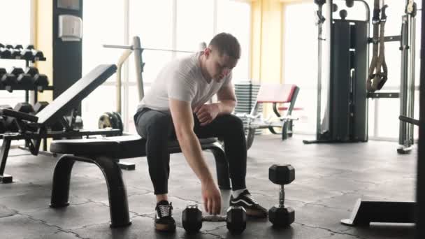 白人男性は激しいジムセッション中に体重を持ち上げることによって彼の身体的能力を示しています 重量挙げを通して彼の強さと力を示す白人選手 — ストック動画