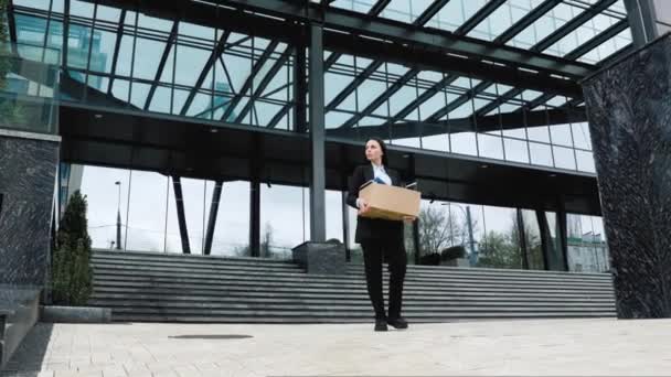 一个女人拿着一个纸盒的户外 上面写着她被解雇了的工作 这反映了她在穿过城市时失去了工作 — 图库视频影像