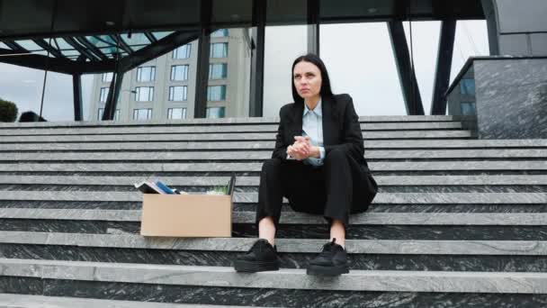一个灰心丧气的女人坐在外面的楼梯上 感受着自己失业状况的压力和勉强度日的挣扎 楼梯上有纸板箱的抑郁女人 — 图库视频影像