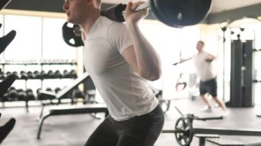 Jimnastik ilham veren halter egzersizleriyle gücünü ve çevikliğini gösteren atletik bir adam egzersiz rutinine heyecan verici bir değişiklik katıyor..