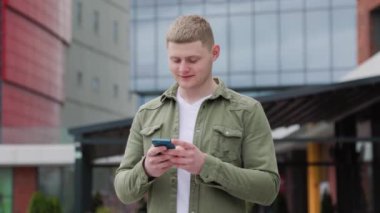 Cep telefonu olan yakışıklı bir çocuk. Cep telefonuyla şehri keşfeden genç bir erkek. Memnun çocuk şehirde akıllı telefonuyla rahatlıyor.