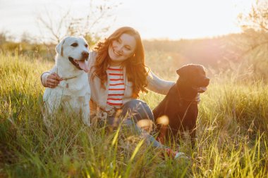 Neşeli Parıldayan Kadın Evcil Köpekleri ile İçten Etkileşim. Kadın ve labradoru gün batımında doğanın güzelliğini kucaklıyor.