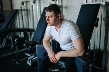 Yorgunluk, yorucu bir spor salonundan sonra çok çalışan bir adamın rahatlama hissi ile karşılaşır. Yorgun bir erkek sporcu spor salonunda sıkı bir idmandan sonra soluklanıyor..