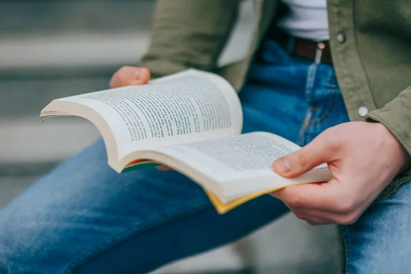 Bu resim öğrenmenin özünü yakına çekerek bir kitabın sayfalarını çevirerek ve her çevirişinde bilgiyi emerek yakalar. Eğitimin Sayfaları Ellerin Kapanışı Bir Kitap Okuyor