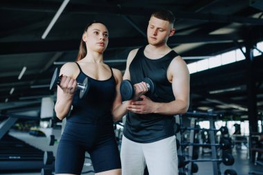 Erkek bir kişisel antrenör, bir kadına spor salonunda uzmanlık ve cesaret sağlayan halter egzersizinde yardımcı olur. Fitness Motivasyon Erkek Antrenörü Spor Salonunda Kadın Asistanı
