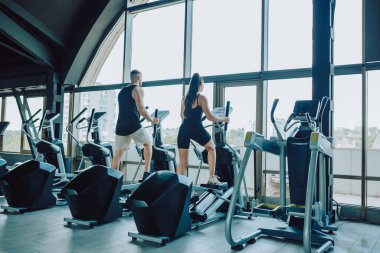 İspanyol bir adam ve beyaz bir kadın spor salonunda zorlu bir güç antrenmanı yapıyorlar. İspanyol ve Amerikalı Çiftin Spor Salonunda Kucaklaşması