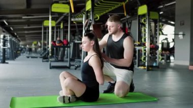 Uzman fizyoterapi uzmanı erkek kayropraktik uzmanı kadın sporculara spor salonunda yardım ediyor. Bir erkek kayropraktik uzmanının spor salonunda bir kadına yardım etmesi.