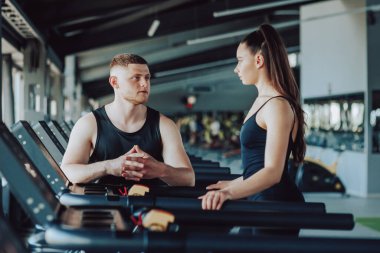 Bilge bir kişisel antrenör ile kadın müşteri arasındaki değerli diyalog, egzersiz rutinleri, fitness ilerlemesi ve daha sağlıklı bir yaşam tarzına giden yolu tartışırken,.