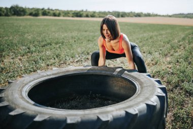  Spor yaparken jimnastik yapan kadın dışarıda tekerleği kaldırıyor. Güçlü Cross Fit Fitness Kadını Tekerleği Dışarı Kaldırıyor