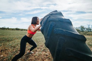 Bir fitness kadınının tekerlek kaldırdığı açık hava egzersiz seansı. Güç ve Kararlılık Çapraz Formda Kadın Tekerleği Kaldırıyor