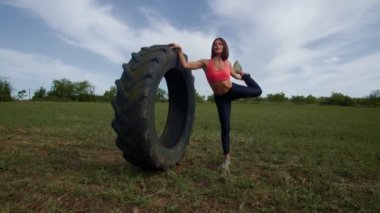 Açık havada spor yapan atletik bir kadın lastikle fiziksel egzersiz yapıyor. Açık havada Güç ve Dayanıklılık Atletik Kadın Lastik Eğitim Haçı