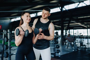 Kendini işine adamış bir erkek antrenör, spor salonundaki halterci için destek ve talimat veren bir kadınla birlikte çalışıyor. Fitness Süreci Erkek Antrenörü Spor Salonunda Kadın Asistanı