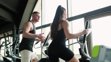 Dayanıklılık ve Koşullandırma. Genç bir kadın spor salonundaki uygunluğunu geliştirmek için bilgili bir erkek antrenörle birlikte çalışıyor..