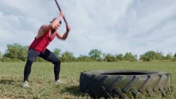 难以置信的力量肌肉男展示了力量 在户外训练用铁锤击打橡胶轮胎 肌肉肌肉肌肉动力冲击橡胶轮胎与锤头交叉配合训练室外 — 图库视频影像