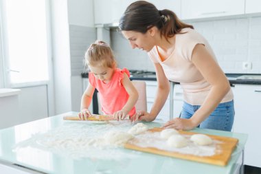 Aile saadeti mutfakta hamuru hazırlarken ve aile birlikteliğinin tadını çıkarırken bir anneyle küçük kızını yakaladı. Mutfak, Bir Anne ve Çocuğun Hamur ile Aile İçinde Yolculuğu