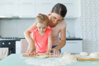 Ev hayatından bir kesit. Bir anne ve kız mutfakta bir araya gelip gülümseyerek ve aile bağıyla hamur hazırlıyorlar. Mutfakta Aile Anları Anne ve Kız Hazırlanıyor