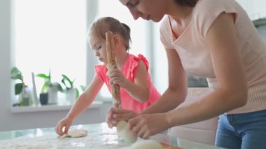 Bir anne ve kız birlikte hamur hazırlarken aile bağları gelişir ve mutfakta unutulmaz bir an yaratır. Aile Mutfağı Sihirli Anne ve Kızı Birlikte Hamur Hazırlayın