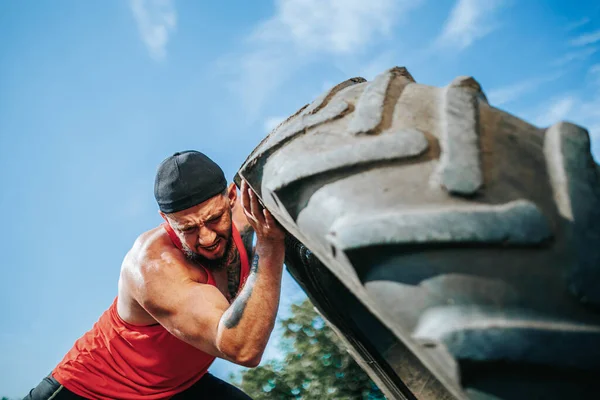 Join this dedicated Cross Fit man in an outdoor workout, where he lifts a wheel with impressive strength and determination, pushing his limits for fitness excellence.