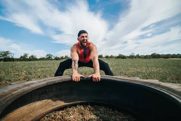 stock image The sportsman demonstrates immense strength and effort as he pulls the wheel during an outdoor Cross Fit training session. Muscular Mans Cross Fit Wheel Pull in Outdoor Setting