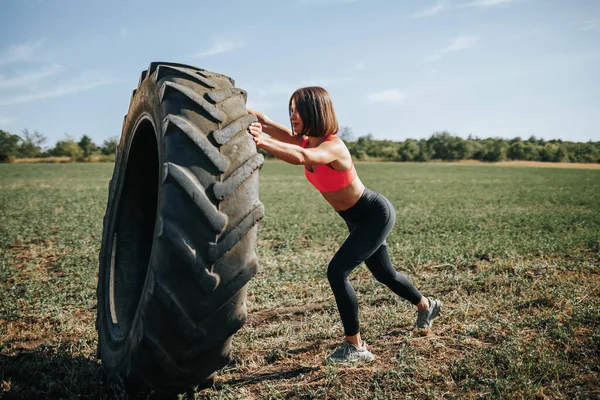Outdoor workout Cross Fit woman engaging in a fitness routine with a lifting wheel. Fit and Determined Cross Fit Woman Exercising with a Wheel Outdoors