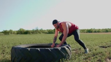 Kas yığını bir adam Cross Fit tekerlek çekme eğitimine katılarak gücünü ve kararlılığını gösteriyor. Çapraz Fit Sporcusu Tekerlek Çekme Eğitimini Dışarda Gösteriyor