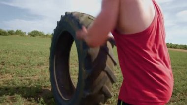 Açık havada CrossFit seansı, erkek sporcuların direksiyon çekme eğitimi sırasında azim ve gücünü yakalar. Kaslı Adam Çapraz Fit Tekerleği Dışarı Çekme Çabası Çalışıyor