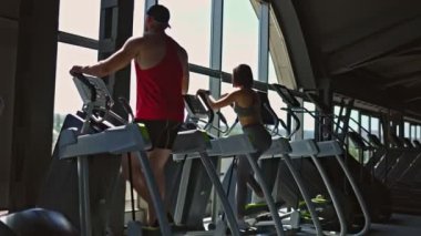 Spor kıyafetleri giymiş iki genç sporcu, bir erkek ve bir kadın spor salonunda güçlü bir idman seansına katıldılar..