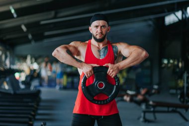 Yetişkin bir sporcu olarak, kaslı bir vücut yapısı ile, ağırlıkları katıksız bir kararlılıkla kaldırır. Spor salonunda ağırlık kaldırma konsantresi