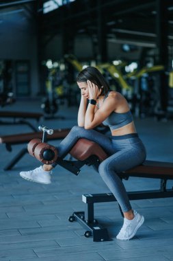 Bir Amerikan Spor Salonu Tutkusunun Aktif Yaşam Tarzı Portresi. Spor Salonunda Güzellik Portresi, yan görünüm Genç Sporcu Kadın Özgüvenle Oturuyor