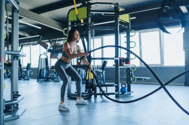 Azimli genç bir kadın spor salonunda bir iple antrenman yapıyor, spor ve atletizme olan bağlılığını gösteriyor. Jimnastik Halatındaki Genç Kadın 'ı Hedefle
