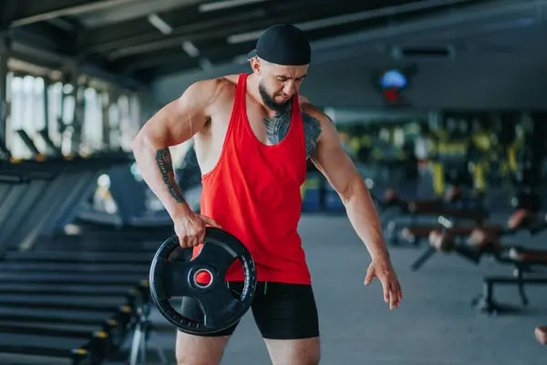 Indoor fitness takes center stage as a sporty male passionately lifts weights, showcasing his muscular physique. Dumbbell Workout Muscular Man in the Gym