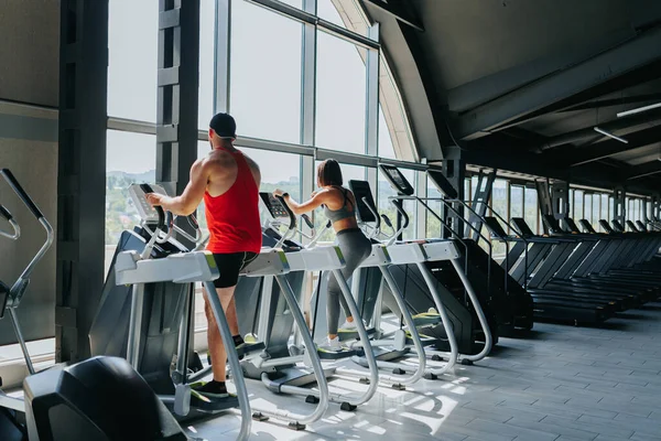 Indoor fitness enthusiasts, including both men and women, are participating in an energetic group workout session at the gym, promoting the benefits of a healthy lifestyle.