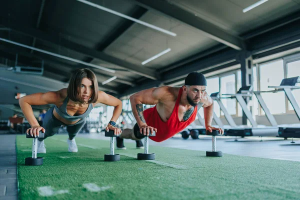 Two sports enthusiasts, one male and one female, are passionately working out with dumbbells in a vibrant gym environment, embodying the spirit of athleticism.