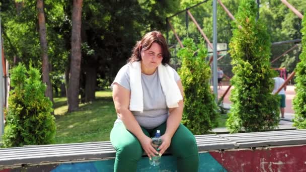 一个肥胖的女人 高加索人 在运动后 站在外面 用她的水瓶喝水 她专心致志于减肥之旅 — 图库视频影像