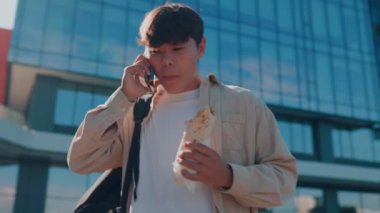 Gülümseyen Öğrenci Hayatı Bir Genç Adam Bir Telefon Sohbetini ve Fast Food Atıştırmasını Beceriklice Yönediyor. Fast Food Yakıt Öğrencileri Harekete Geçmiş Telefon Konuşması