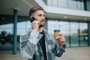 Açık havada cep telefonuyla sohbet eden havalı bir adam şehrin tadını çıkarıyor. Smartphone 'da Amerikan Erkek Konuşmaları