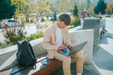 Doğanın güzelliğinin ortasında, çalışkan bir Asyalı Koreli öğrenci kendini bir dizüstü bilgisayara kaptırır. Parkların sakin atmosferi onun ilham verici açık hava sınıfı olarak hizmet veriyor..