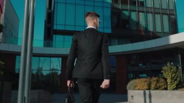 Şık takım elbiseli genç bir girişimcinin arka planda kalan görüntüsü, işlek şehir sokaklarında hızlı bir şekilde gezinirken kendine güveni tam. Urban Hustle Beyaz Yakalı İşçi 4K 'da Başarı İçin Acele Ediyor