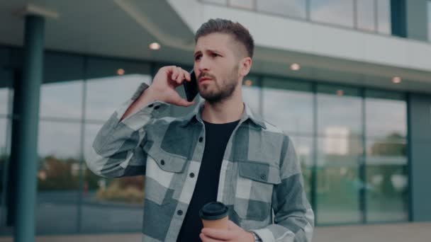Młody Brodaty Mężczyzna Rozmawia Przez Telefon Wygląda Zaniepokojonego Zewnątrz Miejskim — Wideo stockowe