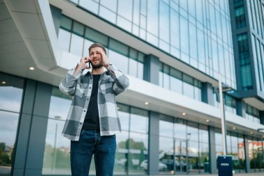Genç sakallı bir adam, şehir merkezinde bir telefon görüşmesi sırasında gözle görülür bir şekilde üzülür. İspanyol adam cep telefonunda bir sorunu tartışıyor, üzgün görünüyor.