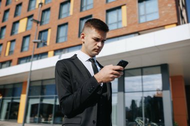 İş bölgesi, beyaz takım elbiseli beyaz bir Amerikalı genç adam akıllı telefonuyla internete bağlanıyor. Kendine güveni modern teknolojinin rolünü vurguluyor.