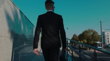 Şehir hayatı hareketli. Profesyonel bir işadamı hareketli sokaklarda koşuşturuyor. Dinamik bir 4K izleme çekimine yakalanıyor. Genç İşadamı İş Bölgesinde Hızlı Hızlı Kariyer Yolculuğu