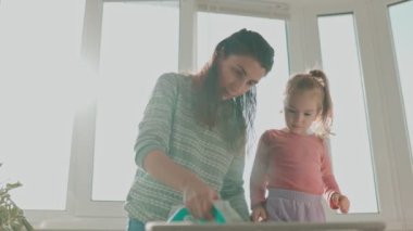 Otantik Anlar Genç Bir Anne ve Kız Evde Ütü Yaparken Uzun süreli Anılar Oluşturur. 4K Ev İşi ve Kaliteli Zamanda Aile