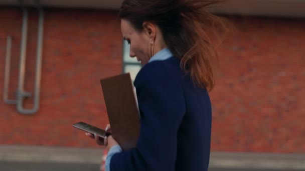 デジタルプロフェッショナリズム よく服を着たアメリカのビジネスマン歩き 彼女の携帯電話を持って 街の通りで自信と近代性を示します — ストック動画