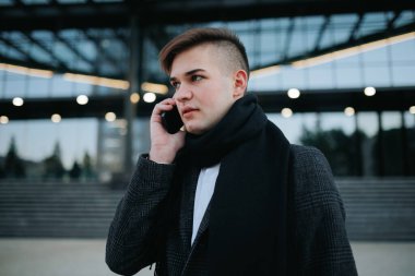 Günümüz iş hayatının dinamik tasviri için teknolojiyi ve kenti kusursuz bir şekilde harmanlayan, cep telefonunu açık havada kullanan sıradan bir iş adamı..