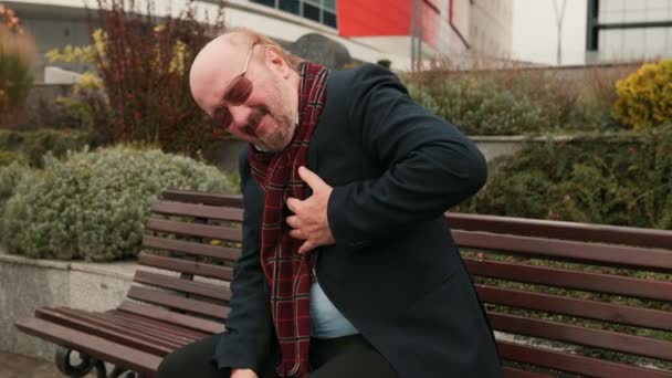 高齢者の健康懸念 不安な上級ひげの男は気分が悪く動揺し 突然の胸の痛みを経験し おそらく市内の心臓発作を信号する — ストック動画